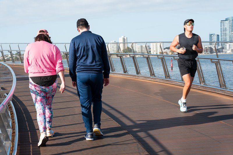 People walking on a bridge over a body of water.