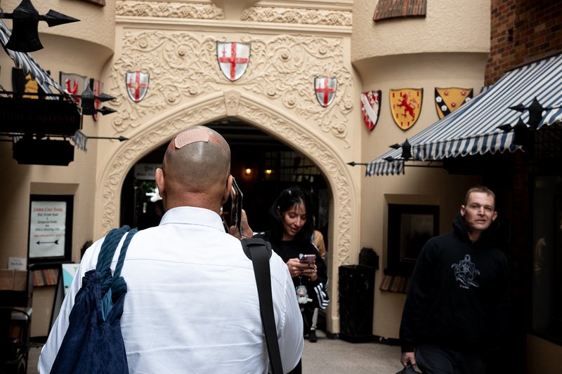 A man with a band-aid on his head takes a photo in front of an ornate archway.