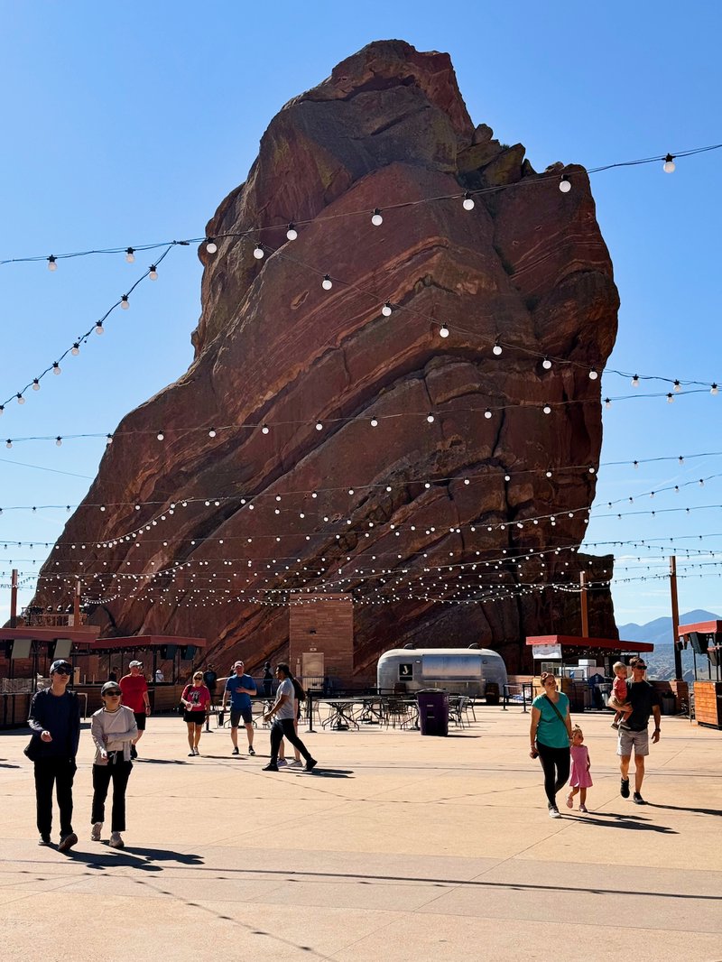 A large rock formation in the middle of a plaza with people walking around it.