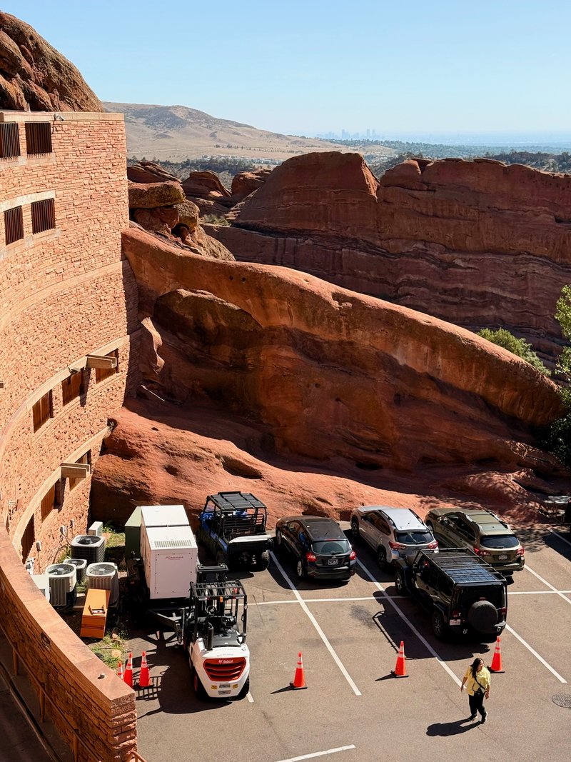 A parking lot with a forklift and orange cones, surrounded by large red rock formations.