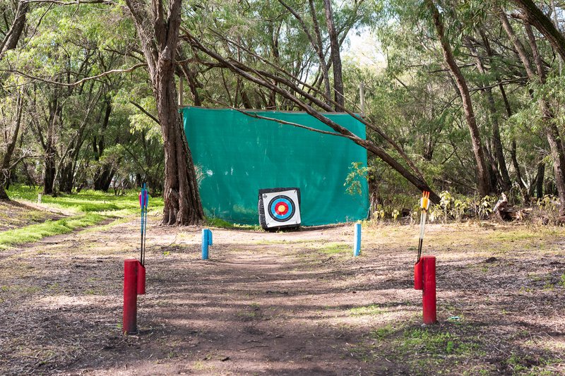 Archery target set in forest, arrows ready for shooting.